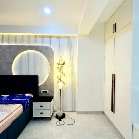 Bedroom with a navy blue channel-tufted bed against a circular backlit feature wall in mottled grey stone-look panelling