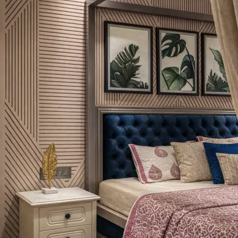 Bedroom with a navy tufted velvet headboard under a metal canopy frame, a botanical leaf-print triptych on a geometric-pattern wallpaper wall