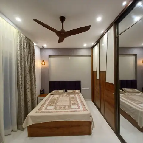 Bedroom with a purple channel headboard and teak bed base facing a full-height mirrored sliding wardrobe that reflects the whole room