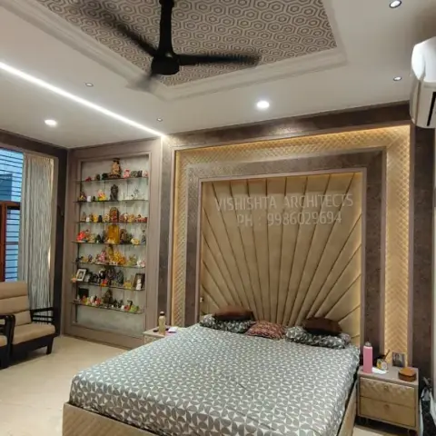 Bedroom with a radial channel-tufted gold fabric headboard wall bordered by textured wallpaper, a hexagon-patterned printed ceiling