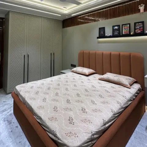 Bedroom with a rust channel-tufted upholstered bed against a sage headboard wall, a backlit floating ledge of framed posters and figurines