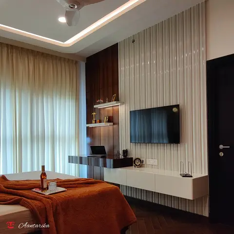 Bedroom with a rust-orange throw folded on the bed, a glossy fluted wall panel behind a wall-mounted TV