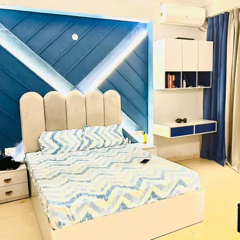 Bedroom with a scalloped upholstered headboard against a blue fluted accent wall featuring a diagonal LED light-strip inlay