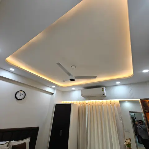 Bedroom with a sculptural curved cove-lit false ceiling over the bed, a black wardrobe door, sheer floor-to-ceiling curtains