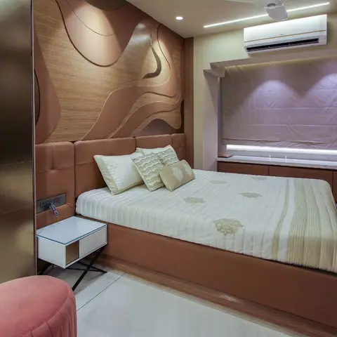 Bedroom with a sculptural wave-pattern wood wall panel behind a terracotta leather-upholstered bed, a bronze mirrored wardrobe