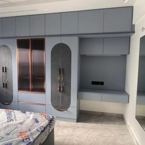 Bedroom with a slate-blue wardrobe featuring oval textured-panel inserts and a fluted glass display column