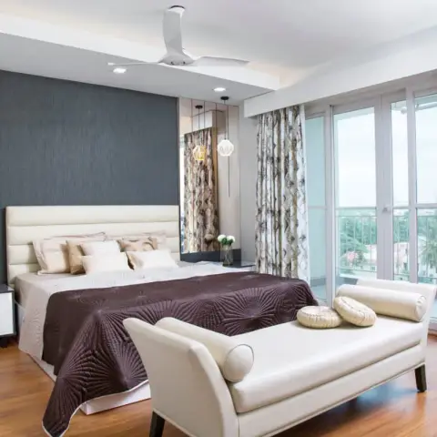Bedroom with a slate-grey fabric headboard wall, mirrored side panel, patterned floor-length drapes, and a balcony beyond the sliding doors