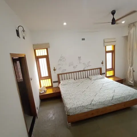 Bedroom with a slatted teak platform bed set against a faint hand-drawn line mural inside a penciled arch