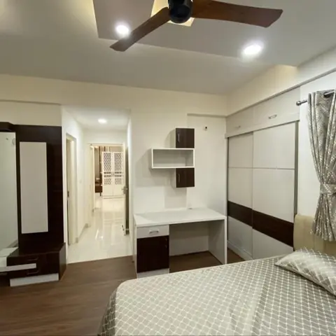 Bedroom with a sliding wardrobe in white and walnut laminate, a compact wall-mounted study desk, and a floor-length dresser mirror, wood flooring throughout.