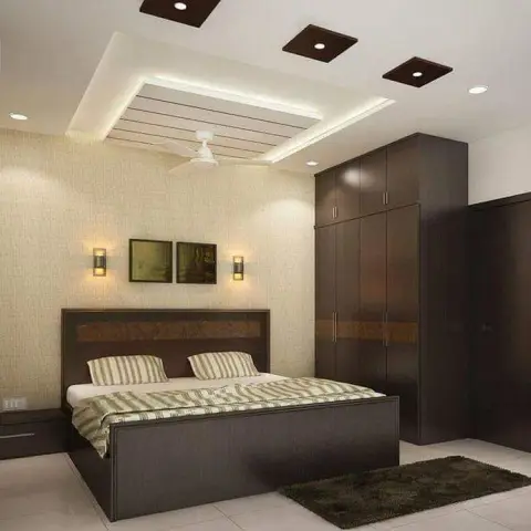 Bedroom with a stepped POP false ceiling with cove lighting, a dark wood panelled bed, and a matching floor-to-ceiling wardrobe.