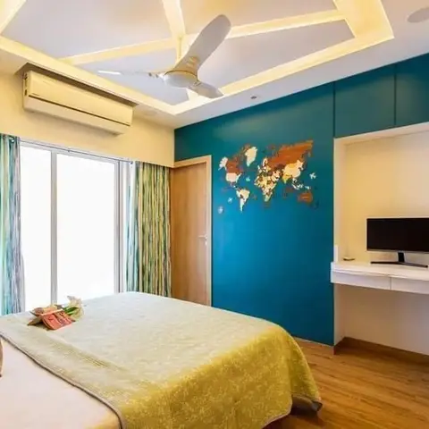 Bedroom with a teal accent wall featuring a decorative wood world-map art piece, a geometric cove-lit POP ceiling, and a floating white TV console.
