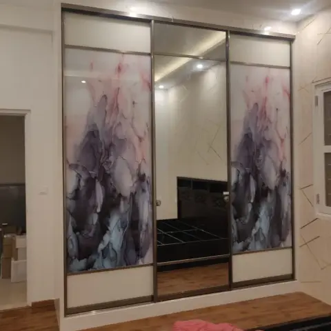 Bedroom with a three-door sliding wardrobe featuring abstract pink-grey marbled glass shutters and a full-height mirror panel, wood-look flooring