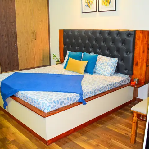 Bedroom with a tufted black leather headboard set in a warm wood surround with an integrated corner nightstand