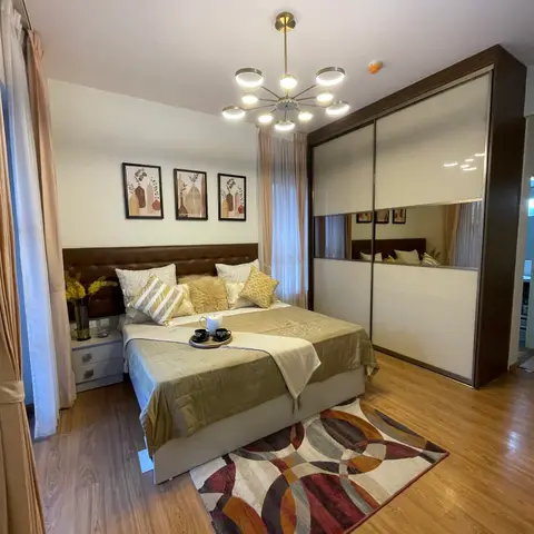 Bedroom with a tufted brown leather headboard, olive-gold bedding, a gold sputnik chandelier and a full-height mirrored sliding wardrobe beside a geometric