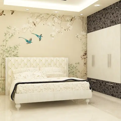 Bedroom with a tufted cream upholstered bed against a bird-and-blossom wallpaper accent wall, beside a dark floral-patterned wardrobe with a mirror panel.
