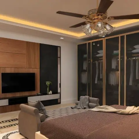 Bedroom with a walk-in glass-front wardrobe, fluted wood TV panel, cove-lit ceiling and an ornate crystal chandelier fan above a brown upholstered bed.
