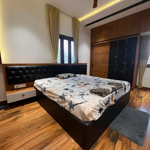 Bedroom with a wall-to-wall black tufted leather headboard and matching bed frame, a wide-plank wood floor