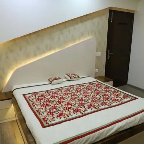 Bedroom with a white angular headboard panel cut in a sloping wing, backlit by a concealed LED strip against a gold-mottled textured wall