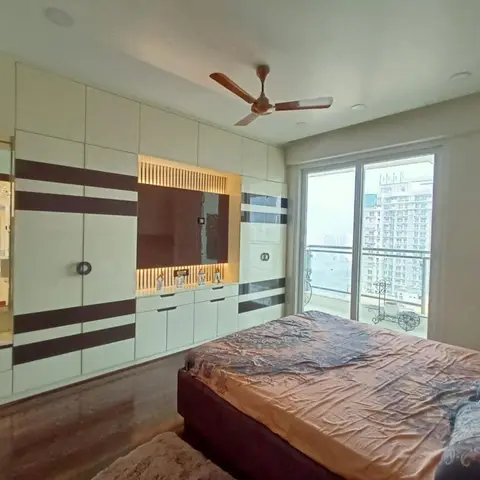 Bedroom with a wide black-and-white striped wardrobe and TV unit wall, a mirrored dressing counter, and a balcony overlooking high-rise towers.