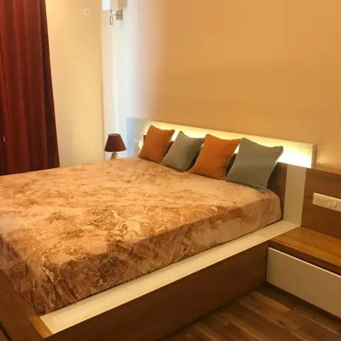 Bedroom with a wood-laminate platform bed lit from behind a white headboard band, a cantilevered bedside carrying the switch plate