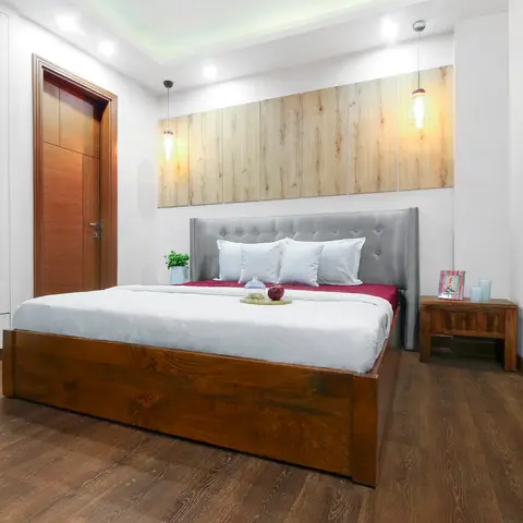Bedroom with a wood-slat panelled headboard wall lit by two hanging glass pendant lights, a grey tufted headboard, a solid-wood storage bed