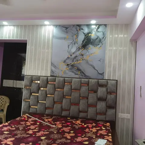 Bedroom with a woven grey-and-gold channel headboard, a marble-effect gold-veined wall panel above the bed, and fluted white wall panelling either side.