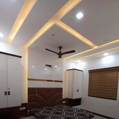 Bedroom with an angular multi-level cove-lit false ceiling, a brown quilted-leatherette headboard