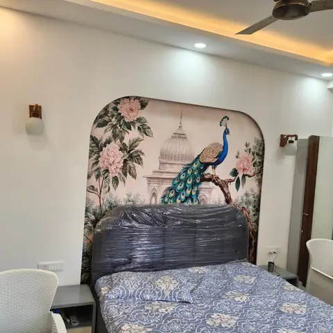 Bedroom with an arch-topped peacock-and-peonies mural panel behind the bed, the upholstered headboard still shrink-wrapped in plastic