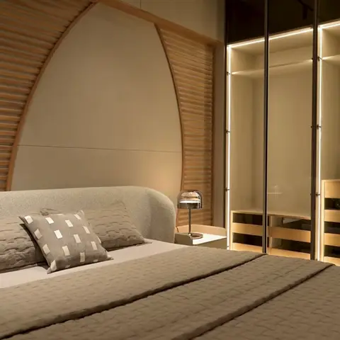 Bedroom with an arched wood-slat feature wall rising behind an upholstered bed, and a glass-front open wardrobe glowing with internal LED shelf lighting.