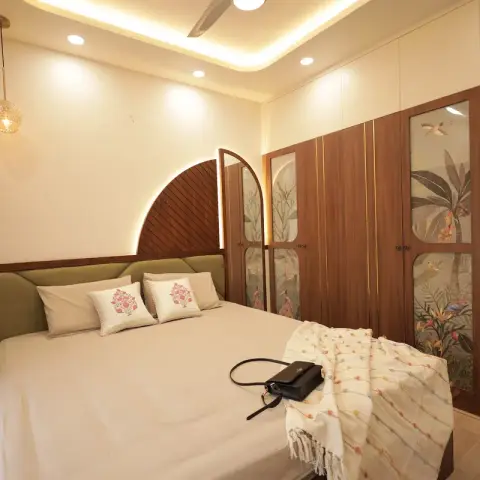 Bedroom with an olive upholstered headboard set against a backlit half-arch of diagonal fluted wood