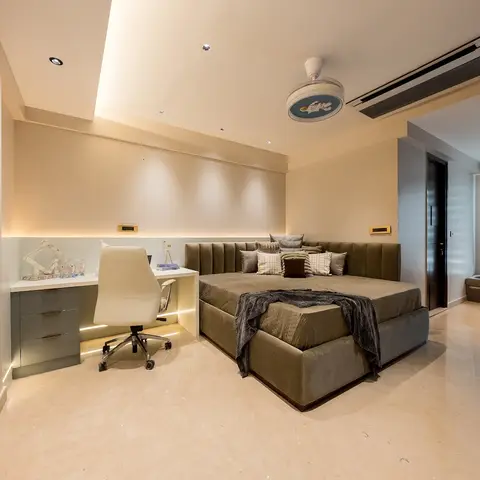 Bedroom with an olive velvet upholstered bed beside a built-in study desk with a white ergonomic chair