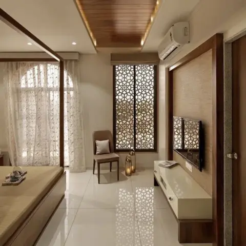 Bedroom with an ornate wood-framed jaali screen at the window, a wood-clad cove ceiling, and a matching jaali-inlay TV unit.