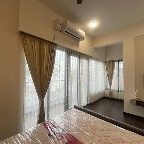 Bedroom with floor-to-ceiling sheer and gold curtains along a corner window, a wall-mounted TV console, and dark wood flooring
