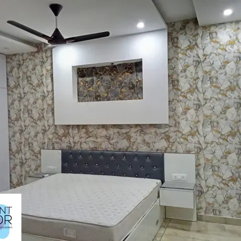 Bedroom with gold-veined marble-pattern wallpaper covering the full wall, a recessed art niche above a black tufted-leather headboard