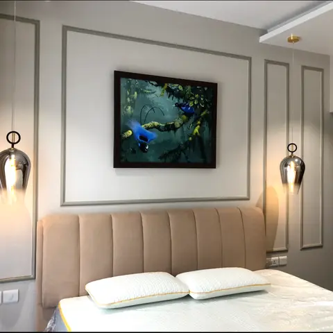 Bedroom with grey moulded wall panels framing wildlife art above a channel-tufted beige headboard, flanked by smoke-glass pendant lights.