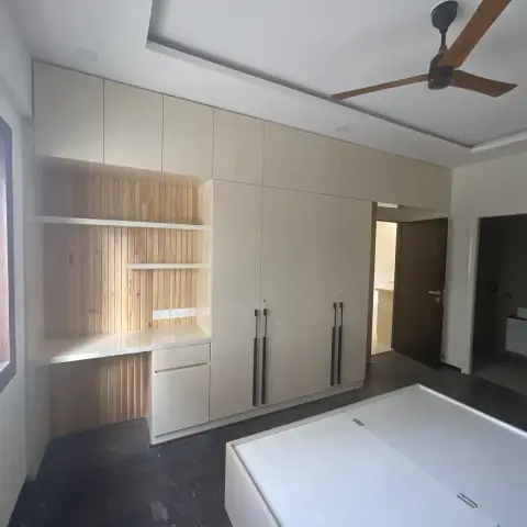 Bedroom with joinery just installed: cream matt wardrobe run with lofts and slim dark handles