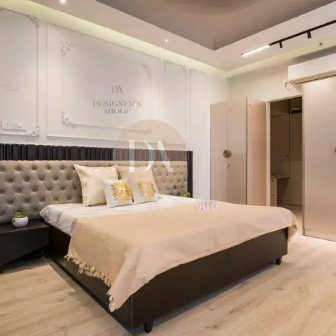 Bedroom with ornate white plaster mouldings above a two-tone headboard wall of dark fluted panelling over a grey button-tufted back
