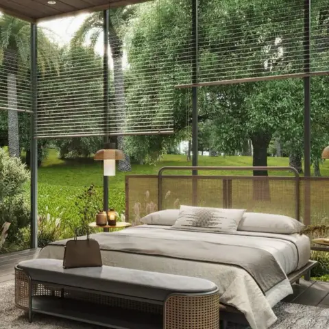 Bedroom wrapped in full-height garden glazing, with a cane-panel headboard in a dark metal frame