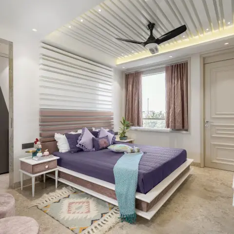 Bedroom wrapped in white horizontal slat panelling that runs from wall onto ceiling, with a blush slatted headboard