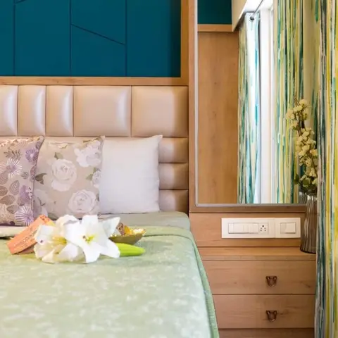 Bedside detail with a teal grooved panel above a cream leatherette channel headboard