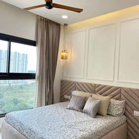 Beige chevron-stitched headboard wrapping into the corner below white wall mouldings and a cove strip