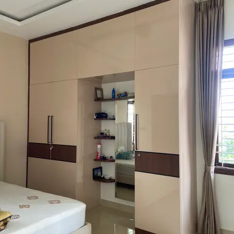Beige gloss wardrobe wall with a wenge band and long black handles, opened up in the middle for a dressing niche of curved corner shelves and a full-length