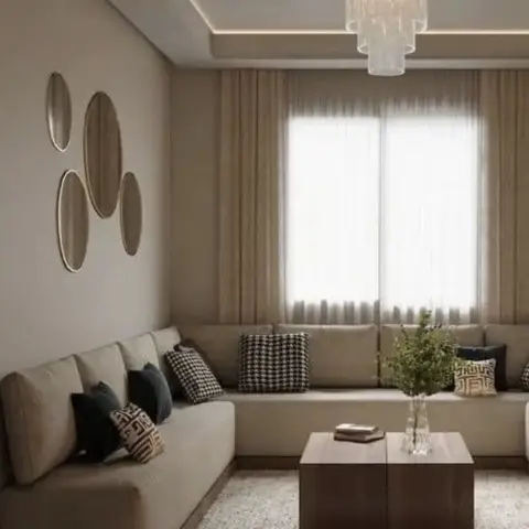 Beige-on-beige sitting room where a low armless sofa runs the full length of two walls