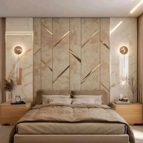 Beige upholstered headboard wall inlaid with gold zigzag strips, flanked by veined marble slab panels and brass sconces with crystal drop rods over pale oak