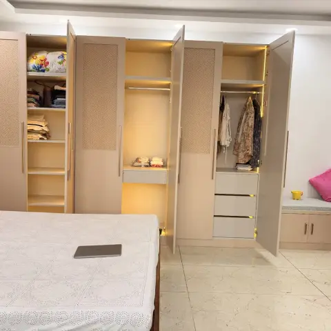 Beige wardrobe run photographed with every shutter swung open to show the LED-lit hanging rails, folded stacks and drawer bank