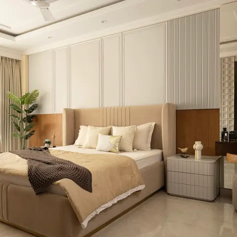 Beige wingback upholstered bed against a white-panelled and wood-clad wall, with an adjoining dressing table and round mirror to the right.