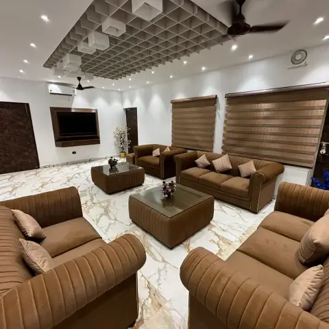Big formal drawing room with four brown channel-tufted sofas ringing two matching upholstered coffee tables on gold-veined white marble