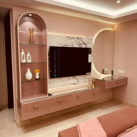 Blush-pink high-gloss bedroom TV wall with an arched glass-shelf display niche, a white marble slab panel behind the TV, gold leaf-shaped knobs on the drawers