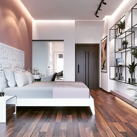 Blush-pink primary bedroom with a carved white jali headboard panel, walnut plank flooring, a black-grid shelving wall styled with plants