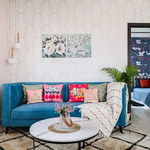 Boho living room with a teal velvet tufted sofa styled with colourful embroidered cushions, geometric gold-line wallpaper, a round marble coffee table